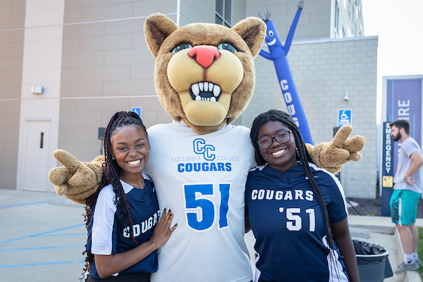 Scooter the Cougar smiling with students.
