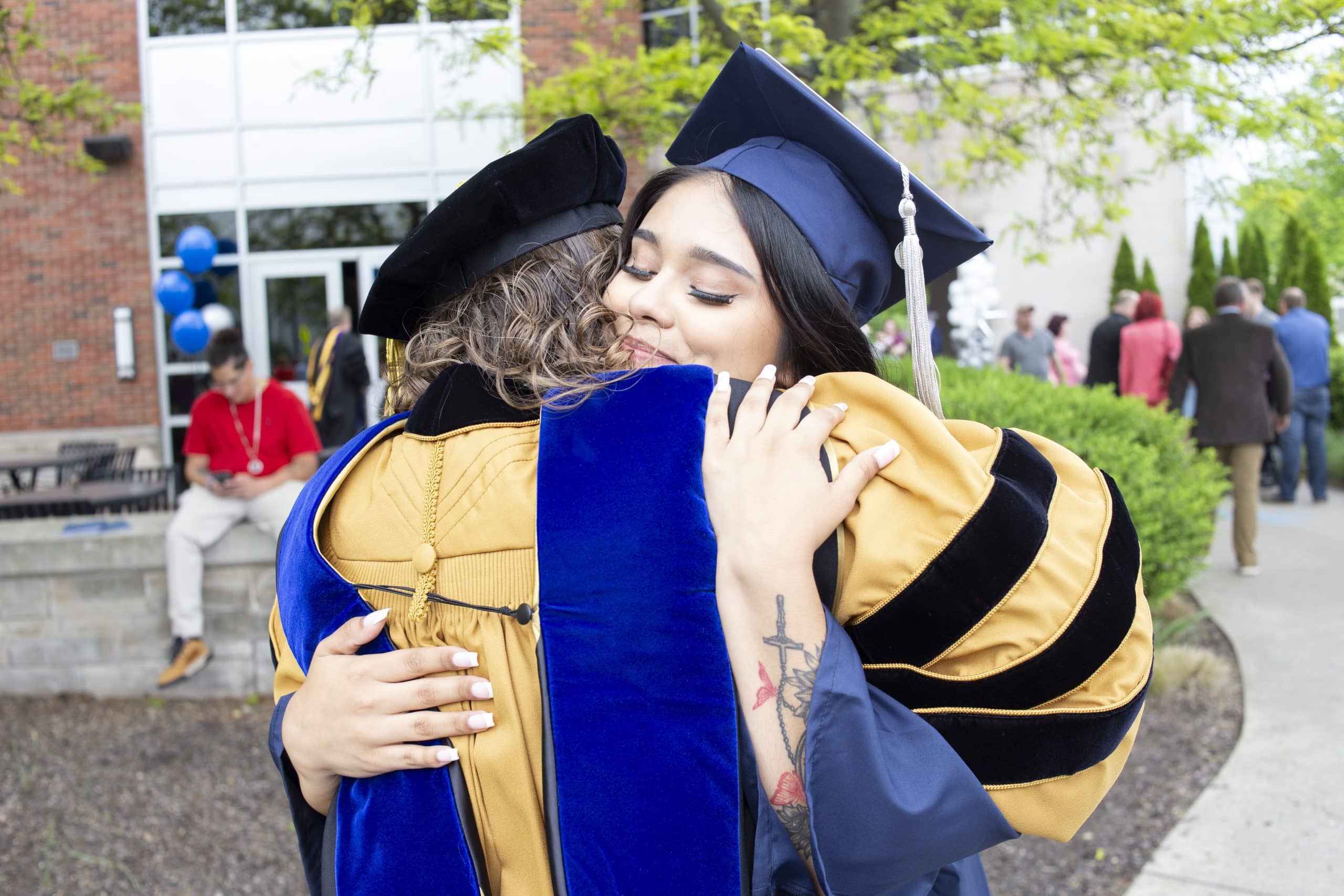 Graduate and faculty member hugging in celebration at the Spring 2024 commencement.