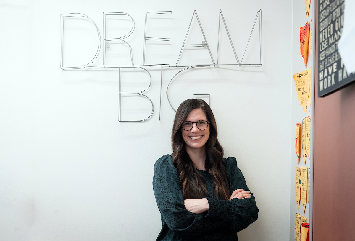 Cassidy Urie '17 standing in front of a wall hanging that says "Dream Big".