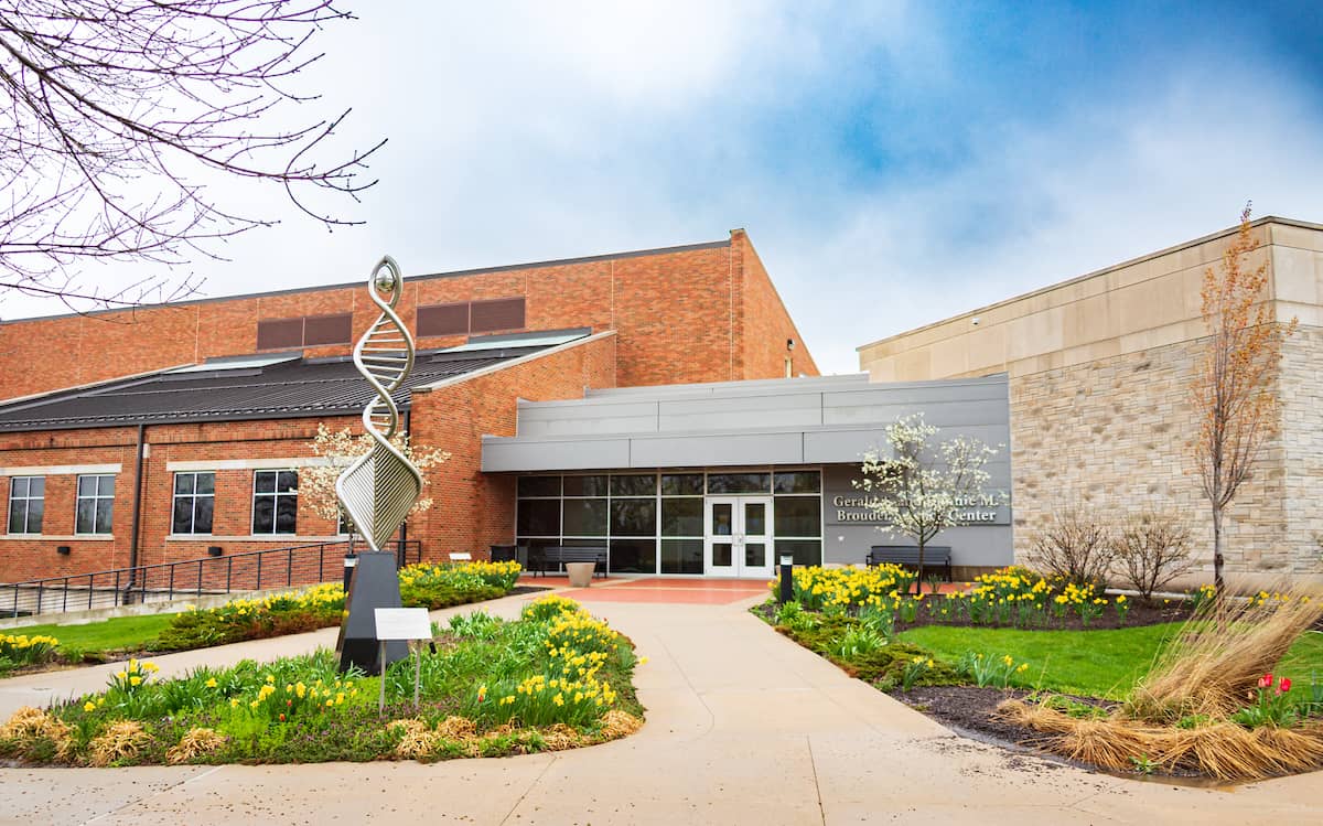 Front view of the Gerald Brouder Science Center building entry, surrounded by yellow blooming flowers.