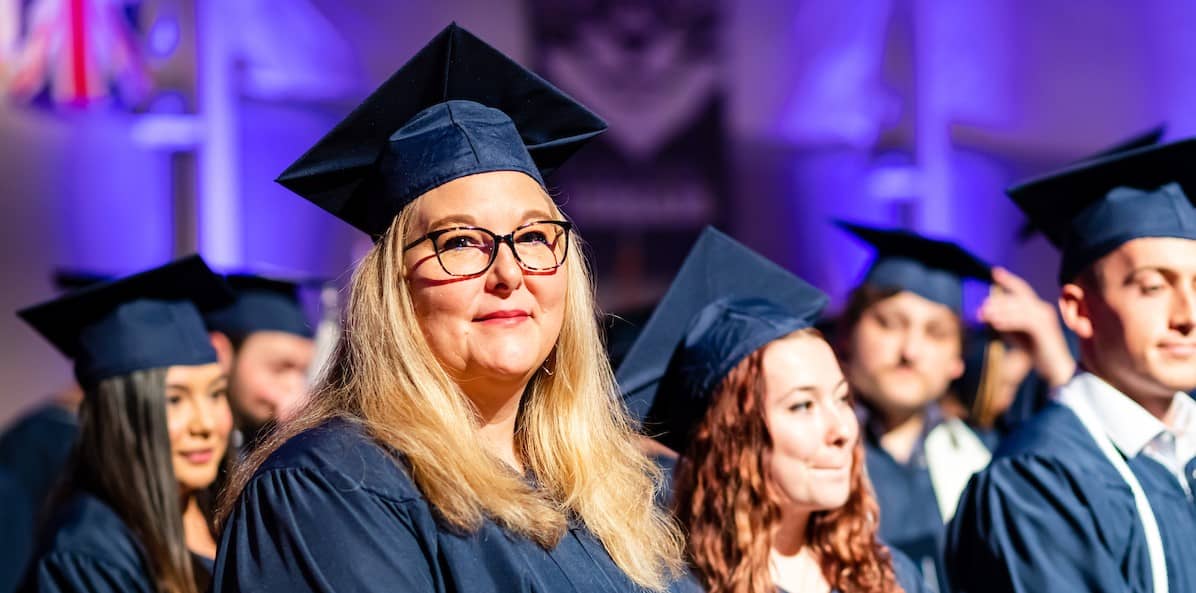 Proud smiling faces of graduates in full regalia at the commencement ceremony.