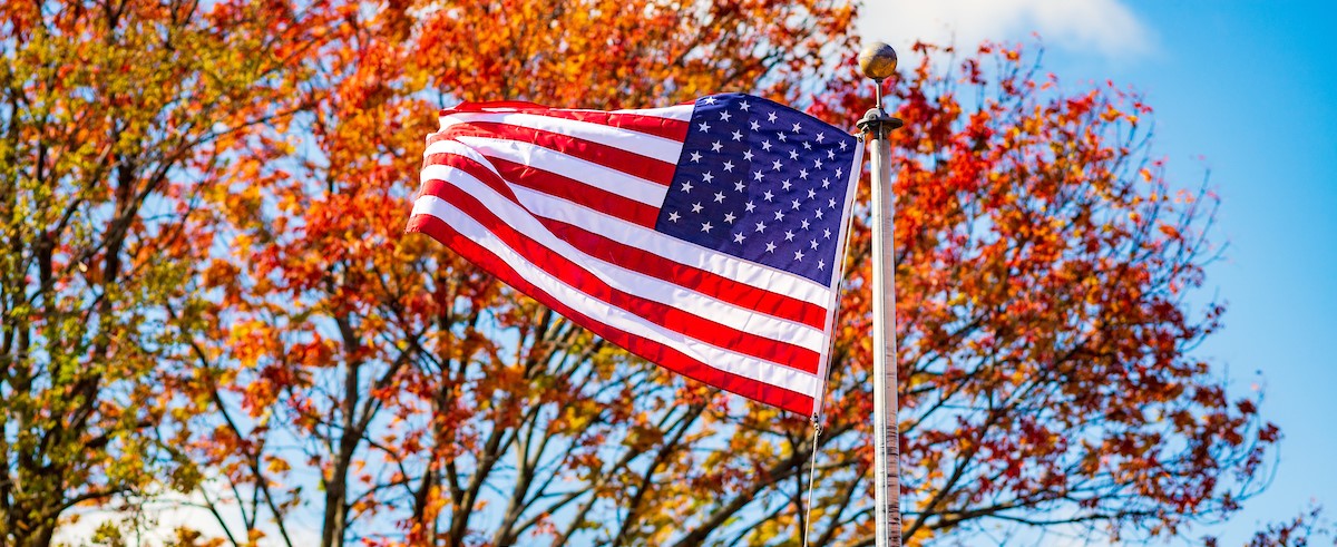 picture of the American flag flying in front of fall foliage.
