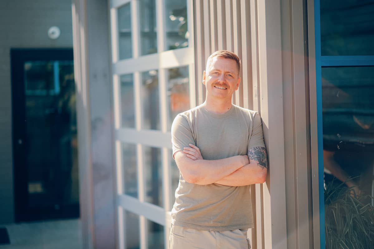 Man with arms crossed wearing military t-shirt, smiling at the camera.